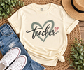 Ivory Comfort Colors teacher shirt with sage heart and pink accent styled in a flat lay with jeans and sneakers