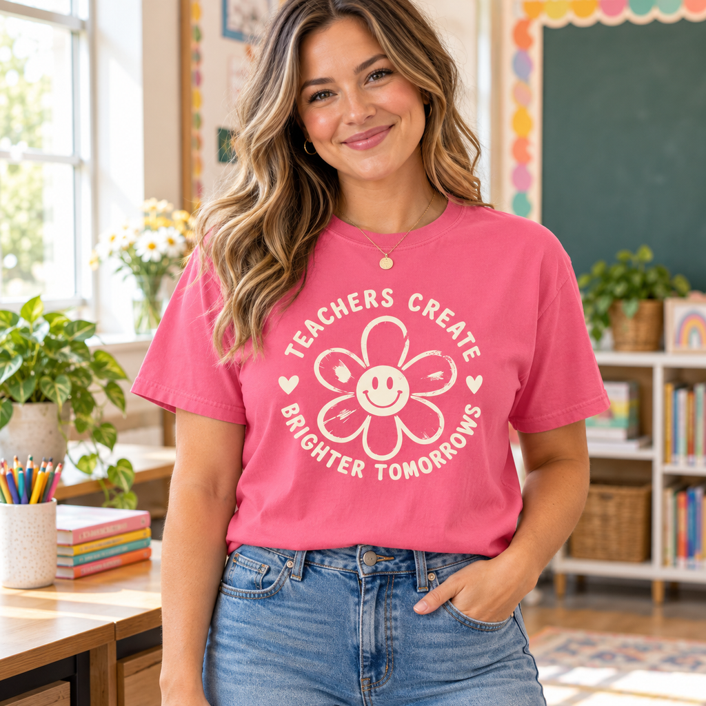 Teacher wearing a Crunchberry pink T-shirt with the cream “Teachers Create Brighter Tomorrows” smiling flower design on the front.