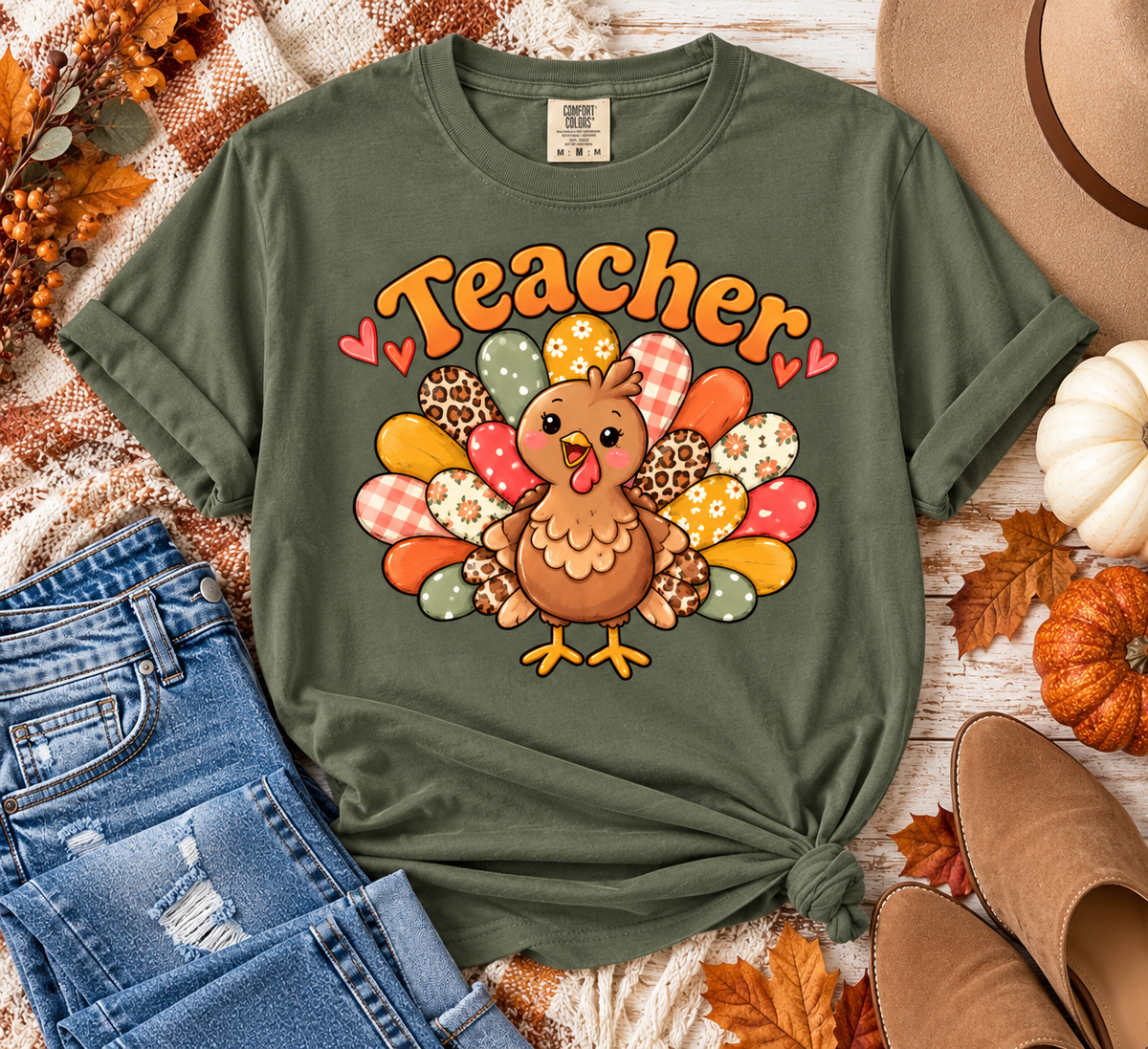 Moss Comfort Colors Thanksgiving teacher shirt featuring a cute turkey with colorful patterned feathers styled in a fall flat lay.